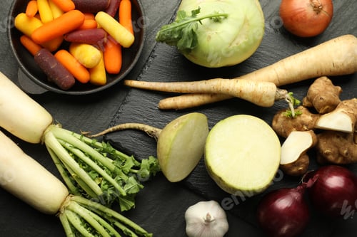 Preview: Different raw root vegetables on black table, flat lay