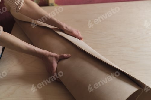 Preview: woman artisan displaying a high-quality leather roll in her workshop, signifying her expertise in