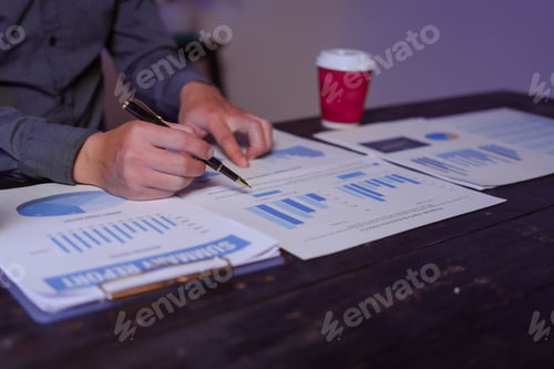 Preview: A close-up of a male businessman at his desk, analyzing overtime graphs business charts finance