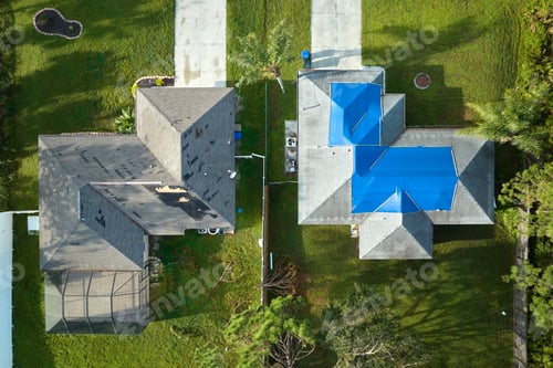 Preview: Top view of leaking house roof covered with protective tarp sheets against rain water