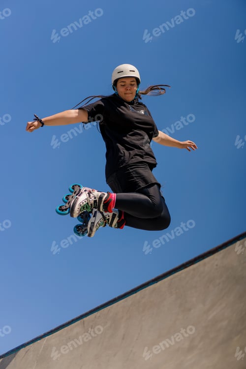 Preview: skilled woman rollerblading and jumping on the ramp in the skate park outside Practicing her tricks