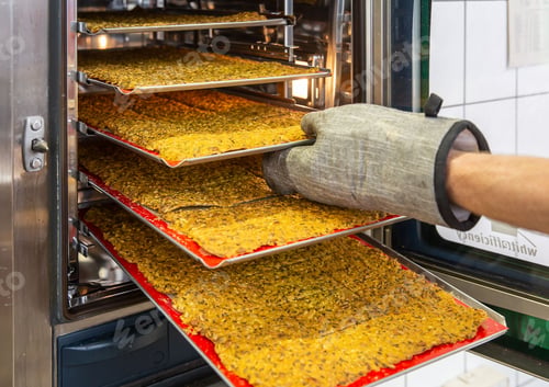 Preview: Close-up of a person taking a freshly baked sheet of crispbread from an oven.