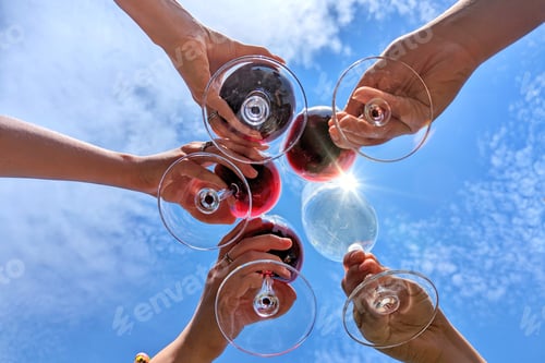 Preview: Cheers!! toasting with wineglasses of wine as seen from below against blue sky with sunlight