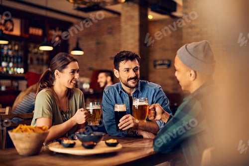 Preview: Happy friends talking while drinking beer in a pub.