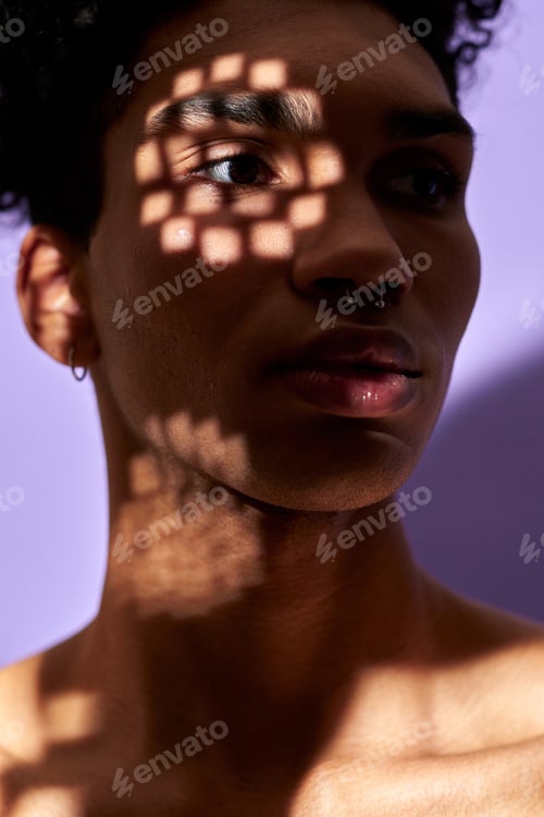 Preview: Close-up verticale portrait of latino young man face in texture shadows, lights on eye