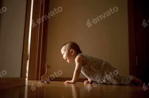 Preview: The baby is crawling on the floor to a wooden toy at home