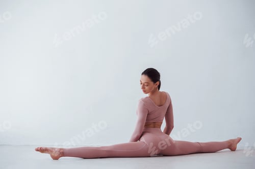 Preview: Doing the splits. Caucasian pretty woman doing exercises against white background in the studio