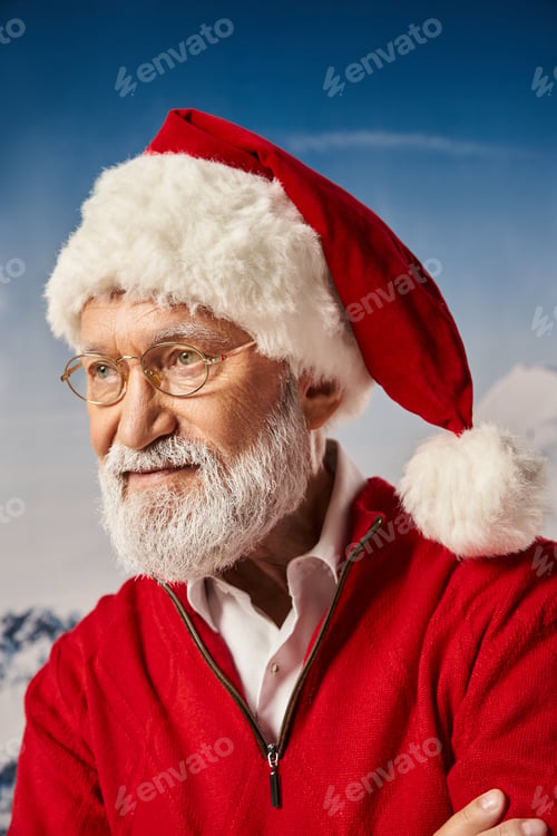 Preview: good looking man dressed as Santa in glasses posing on snowy background looking away, winter concept
