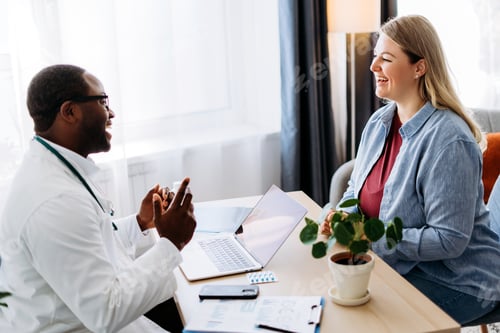 Preview: Happy male African American doctor listening to female patient at his office