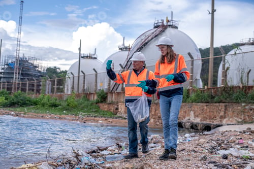 Preview: Environmental scientists or workers, wearing safety helmets and gloves, examining waste materials al