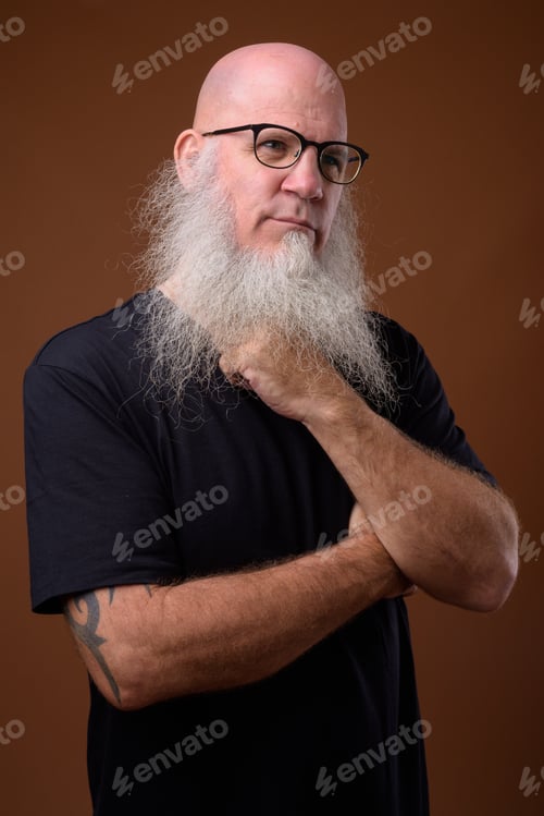 Preview: Mature bald man with long gray beard against brown background