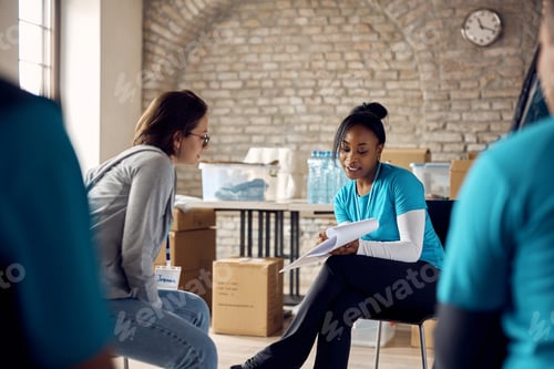 Preview: Black volunteer coordinator giving instructions to her coworker at community center.