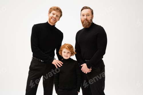 Preview: redhead boy standing with hands in pockets near happy dad and grandpa while smiling at camera