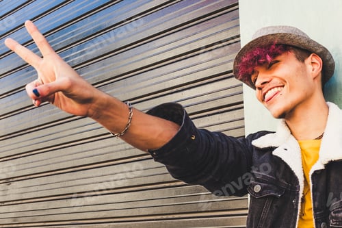 Preview: Happy young teenager boy do victory sign with hand and fingers - portrait of joyful and cheerful man