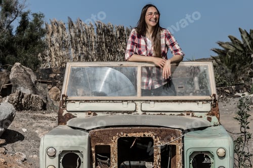 Preview: Smiling woman in sunglasses in old car between deserted lands