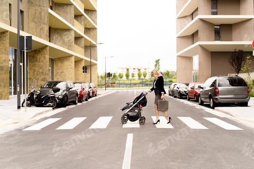 Preview: Young businesswoman with briefcase pushing stroller while crossing the street