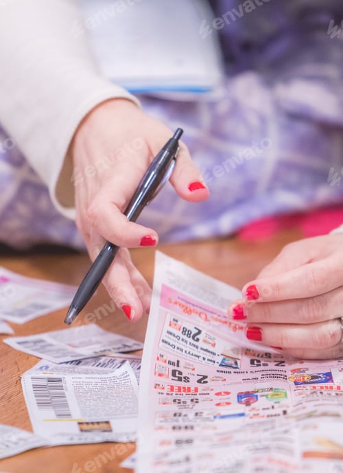 Preview: young millennial woman at home clipping coupons from newspaper