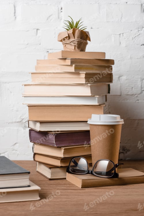 Preview: books, eyeglasses, potted plant and coffee to go on wooden table