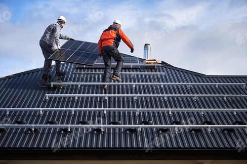 Preview: Technicians carrying photovoltaic solar module while installing solar panel system on roof of house