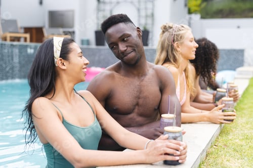 Preview: Diverse group of friends enjoys drinks by the poolside, sharing a cheerful moment
