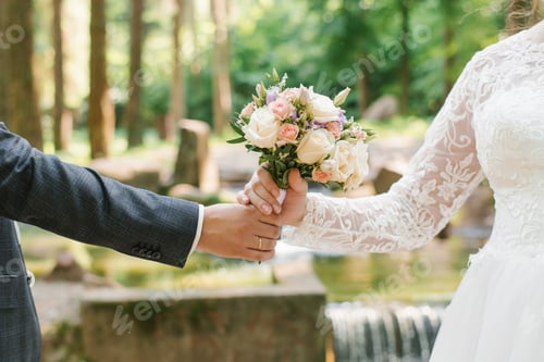 Preview: Groom Holds out Wedding Bouquet to the Bride. Close up of Newlywed Hands and Delicate Bouquet