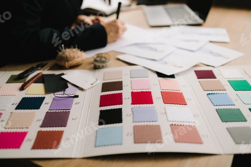 Preview: Designer plans dress designs on paper, preparing patterns and garment layouts.