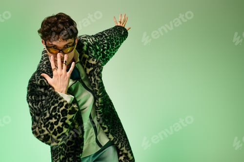 Preview: Stylish man showcasing unique fashion sense in a vibrant green setting during indoor photoshoot