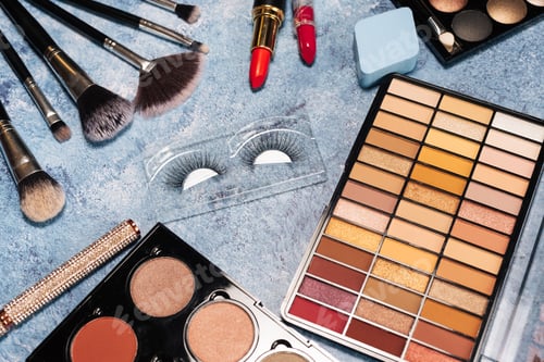 Preview: set of decorative cosmetics, makeup brushes false eyelashes on a blue background. the view from top