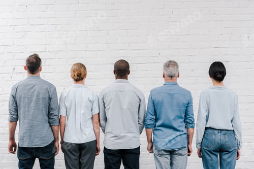 Preview: back view of multicultural people standing near brick wall