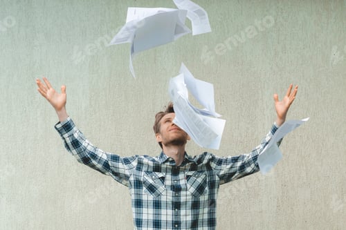 Preview: young stressed man throw crumpled paper files in the air, freedom concepts