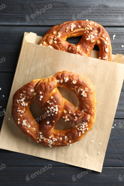 Preview: Tasty pretzels with salt on dark wooden table, top view