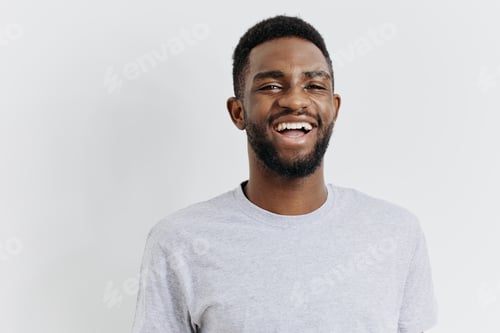 Preview: Confident african american man smiling in casual grey tshirt on clean white background, radiating