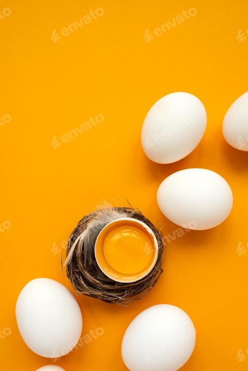 Preview: White eggs and egg yolk into nest on yellow background. Top view. Flat lay. Easter celebration