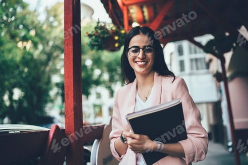 Preview: Half length portrait of cheerful female journalist with sketchbook posing at urban setting