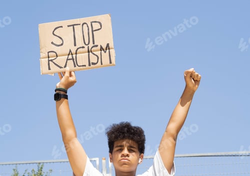 Preview: Afro teenage boy with a sign in his hands with the slogan: stop racism