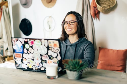 Preview: Happy cheerful woman works on a stylish laptop in the interior of a cozy living room