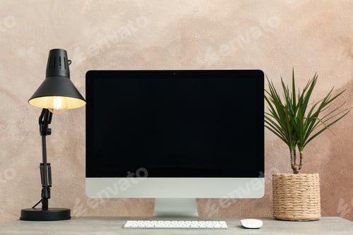 Preview: Workplace with computer and plant on wooden table. Light brown background