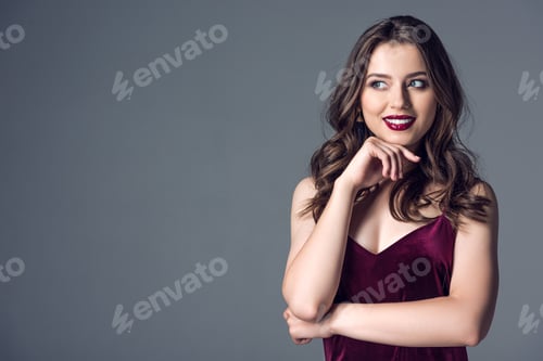 Preview: beautiful young woman in stylish dress looking away isolated on grey