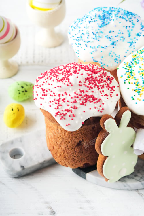 Preview: Traditional Easter sweet bread or cakes with white icing and sugar decor and quail eggs over white w
