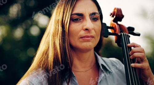 Preview: Cropped shot of a beautiful woman playing a cello in the backyard