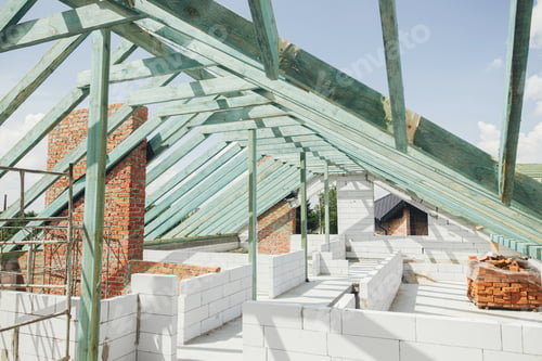 Preview: Unfinished roof trusses, view in attic with rafters, beams, windows and chimney. Wooden roof framing