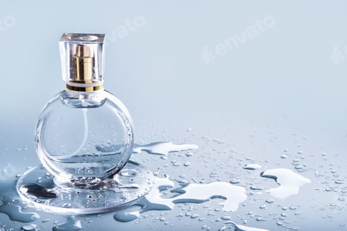 Vista previa: Glass perfume bottle and drops water on blue background. Winter or spring fragrance