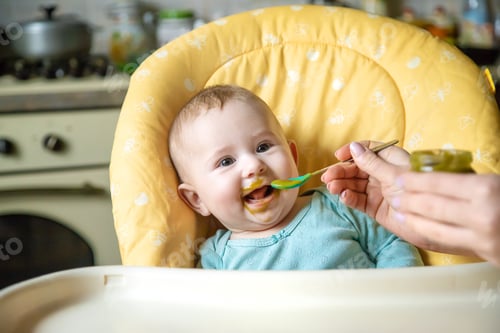 Preview: Little baby is eating broccoli vegetable puree. Selective focus.