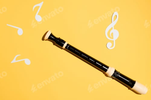 Preview: Flute, notes and treble clef, flat lay on a yellow background. Musical classical instrument