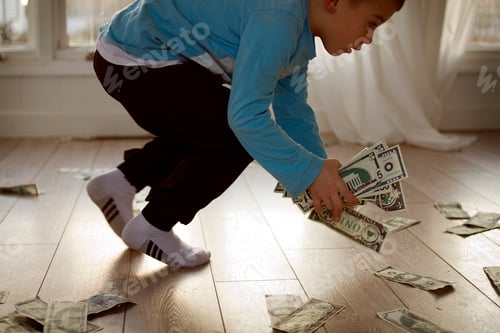 Preview: Little boy picking up fake money off the ground. A lot of toy money.