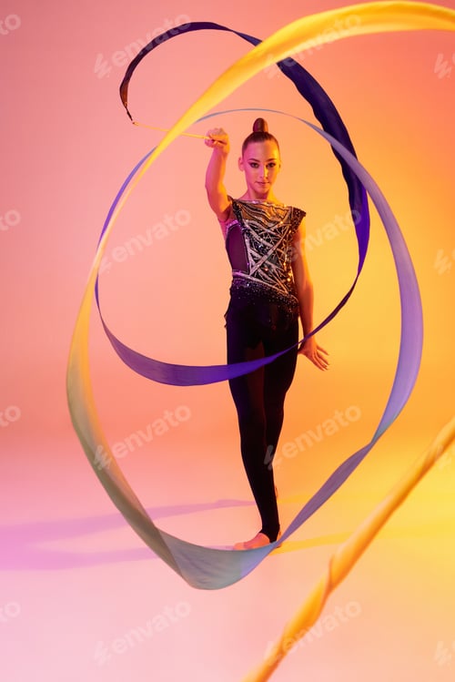 Preview: Portrait of little girl, rhythmic gymnastics artist isolated on pink yellow studio background in