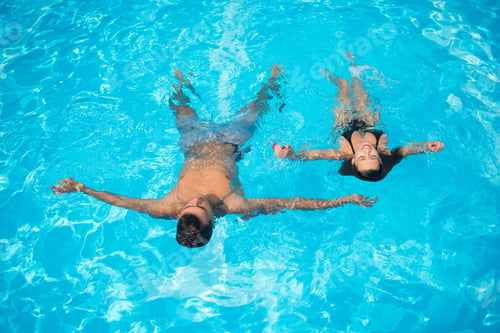 Preview: Couple in love refreshing in the swimming pool on the turquoise water at vacation.