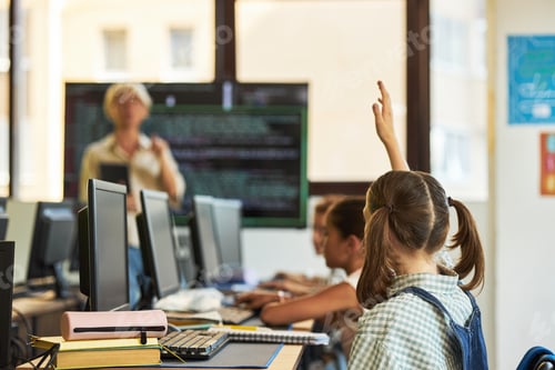 Preview: Teenage Girl Raising Hand While Attending Computer Class with Teacher Present