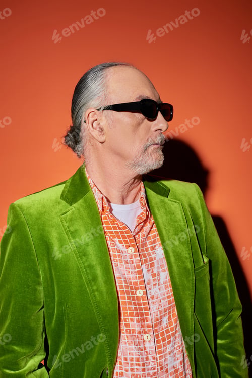 Preview: fashion look, senior male model with grey hair and beard looking away on red and orange background