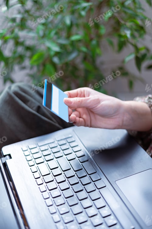 Preview: Close-up of a woman's hand holding a bank card and ready to pay for an online purchase.